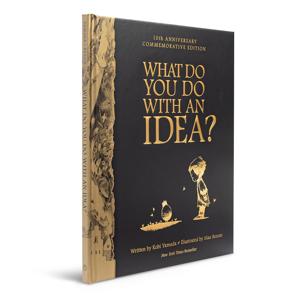 What Do You Do With an Idea? 10th Anniversary Edition by Compendium, black hardcover with gold foil cover and gold-edged pages, angled view on white