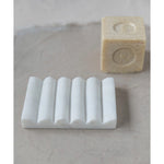 Creative Co-Op Carved Marble Soap Dish with a bar of soap on a stone surface