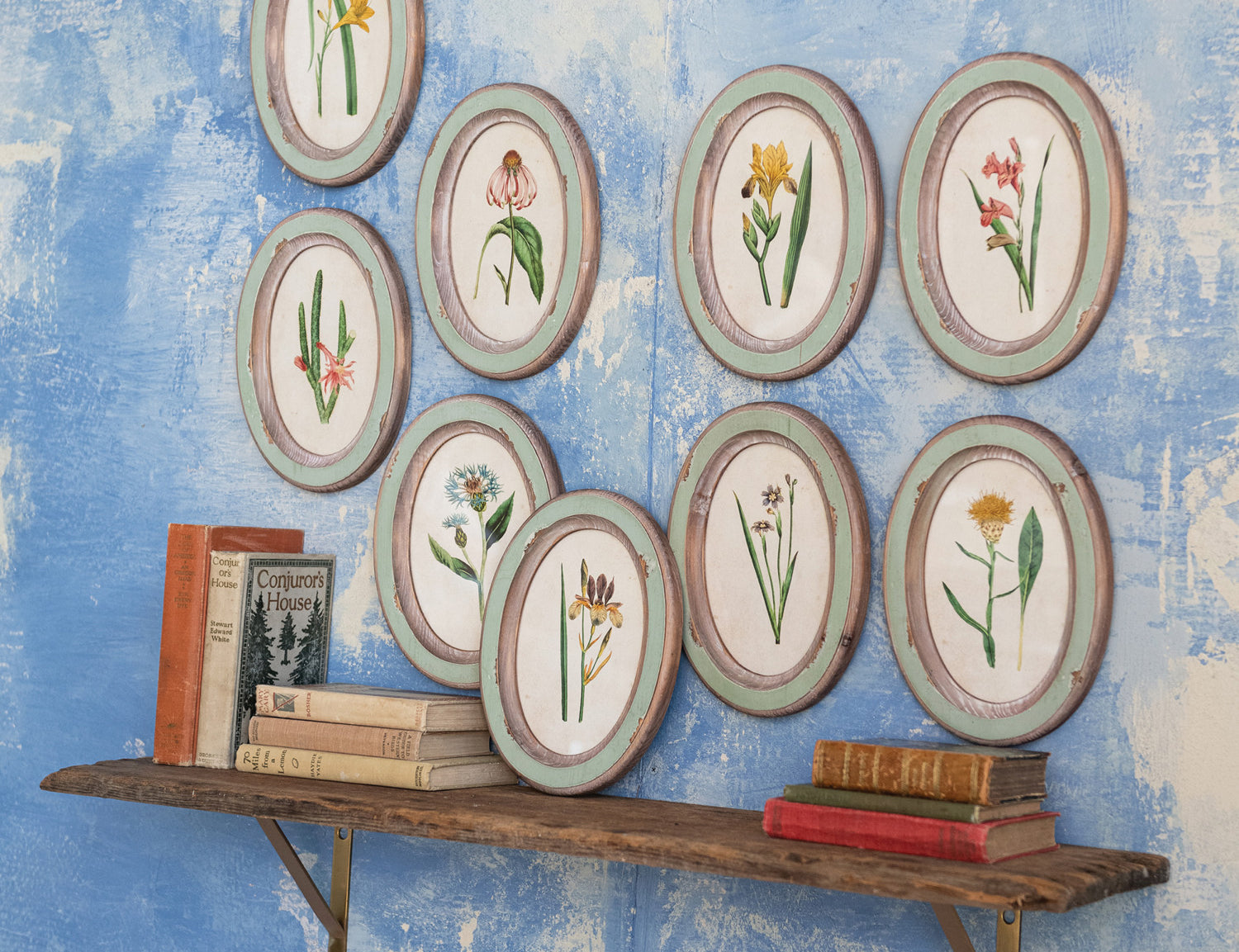 Creative Co-Op Flower Wood Frames arranged on a blue wall above a shelf of books