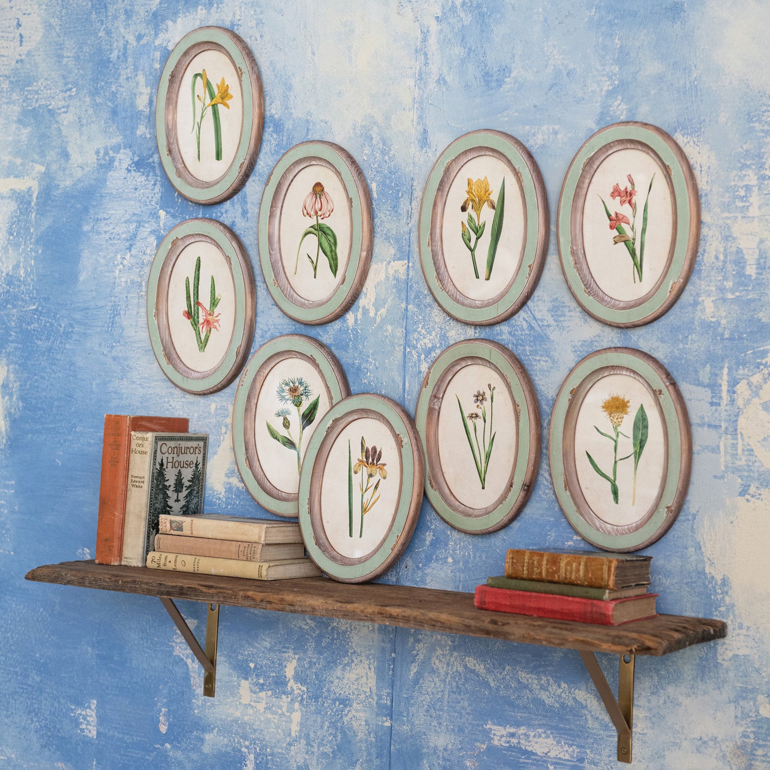 Creative Co-Op Flower Wood Frames arranged on a blue wall above a shelf of books