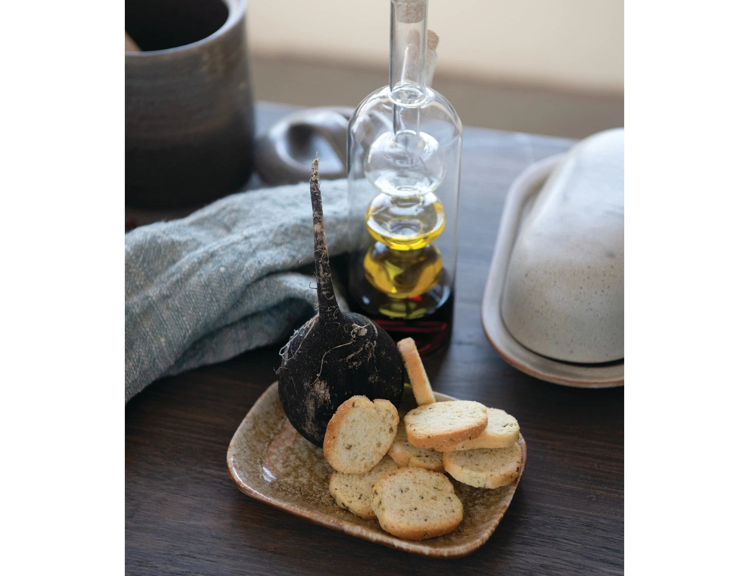 Creative Co-Op Glass Oil and Vinegar Cruet on a dark table with bread slices and a napkin