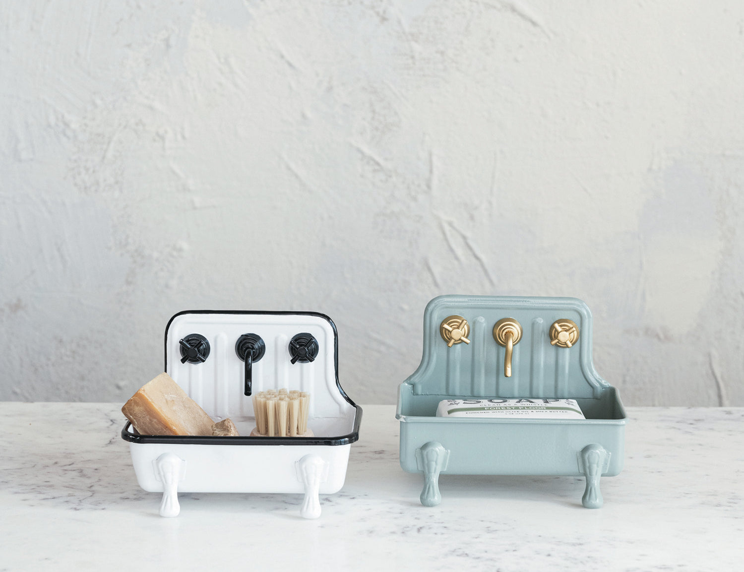 Creative Co-Op Metal Sink Soap Dishes in white and sage holding bars of soap on a marble counter