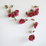 Creative Co-Op Paper Flower Garland hung on a white wall, full view