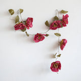 Creative Co-Op Paper Flower Garland hung on a white wall, full view