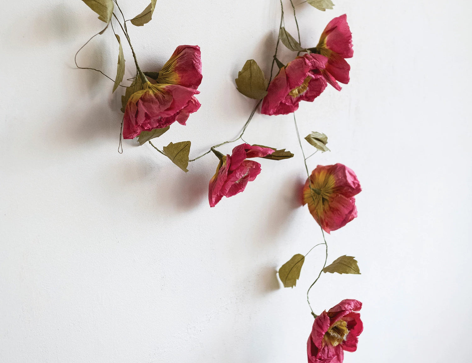 Creative Co-Op Paper Flower Garland draped against a white wall