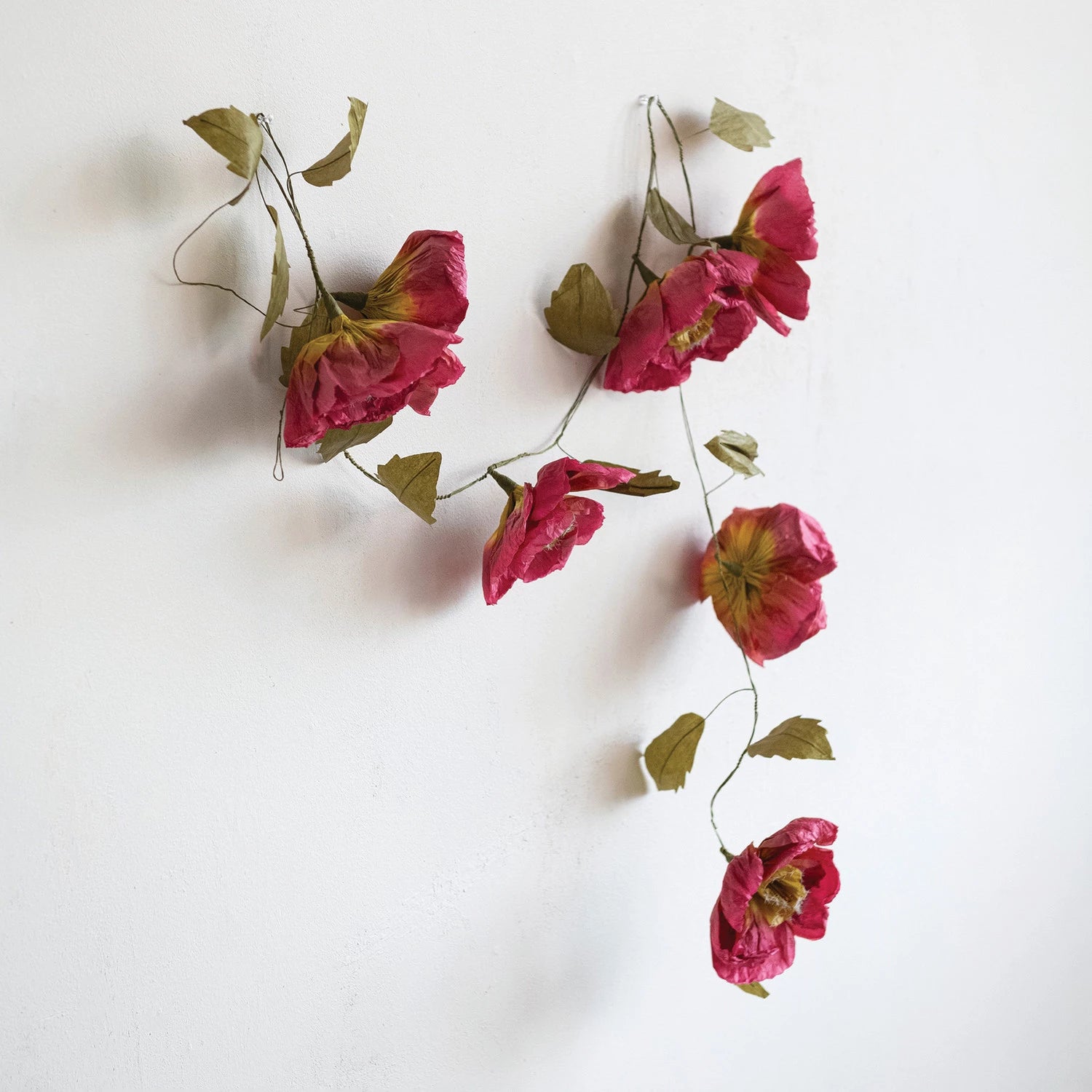 Creative Co-Op Paper Flower Garland draped against a white wall