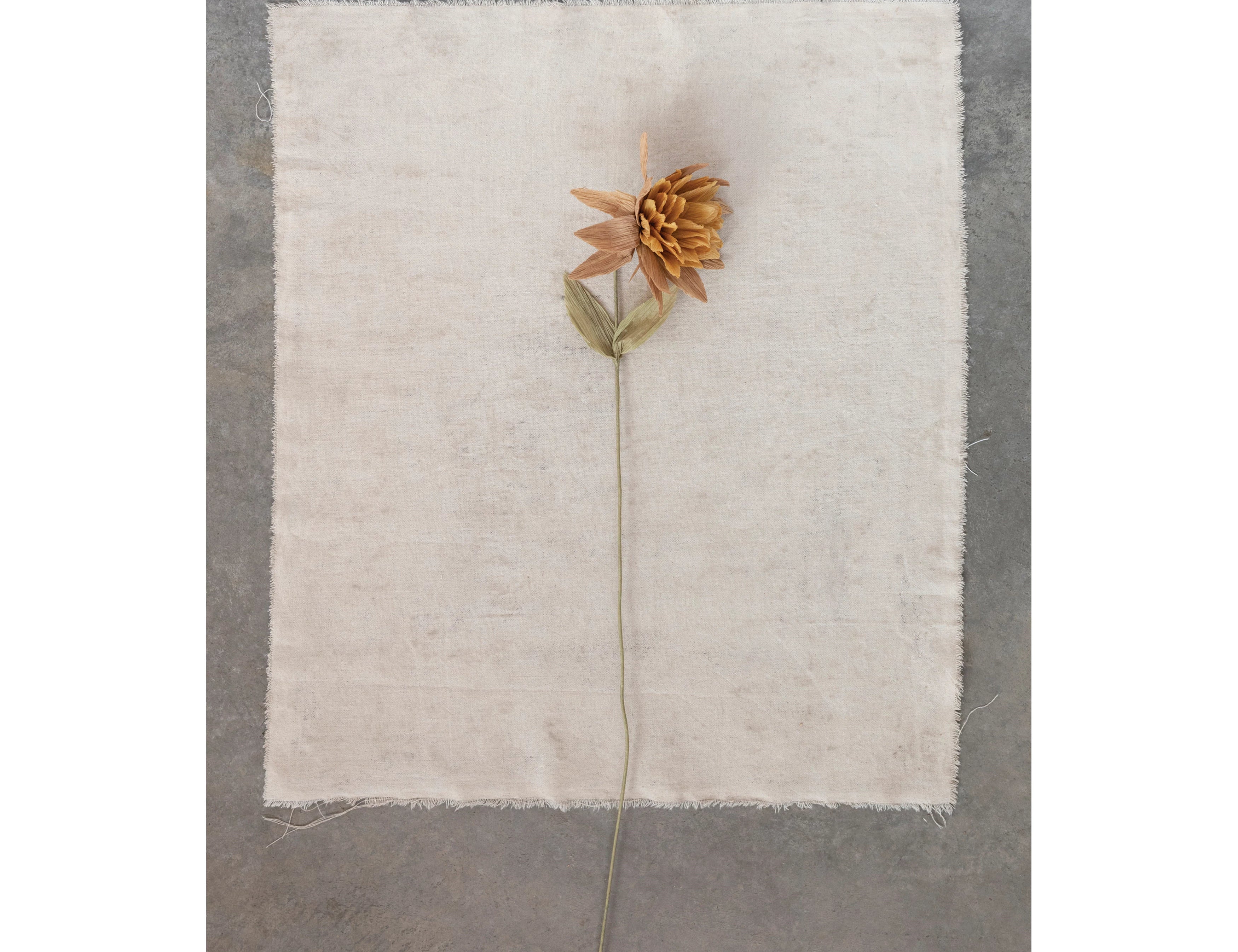 Creative Co-Op Paper Flower Pick in Mustard resting on a linen napkin