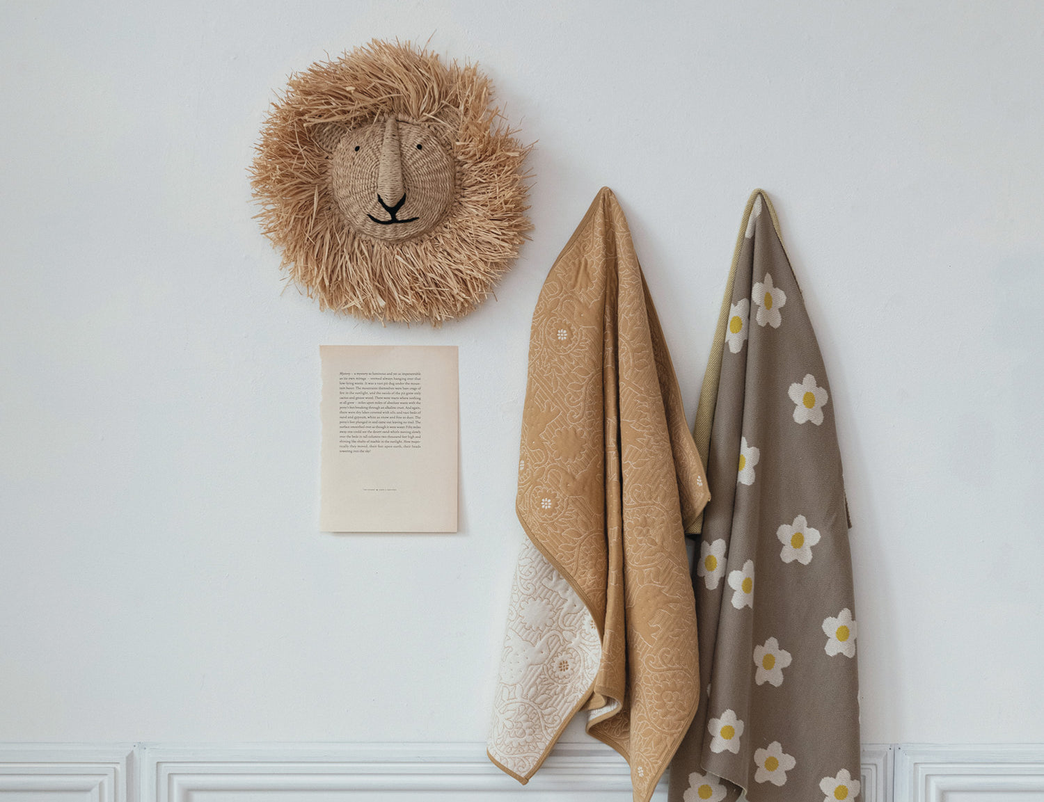 Creative Co-Op Raffia Lion Head Wall Decor hung on a wall above hanging towels