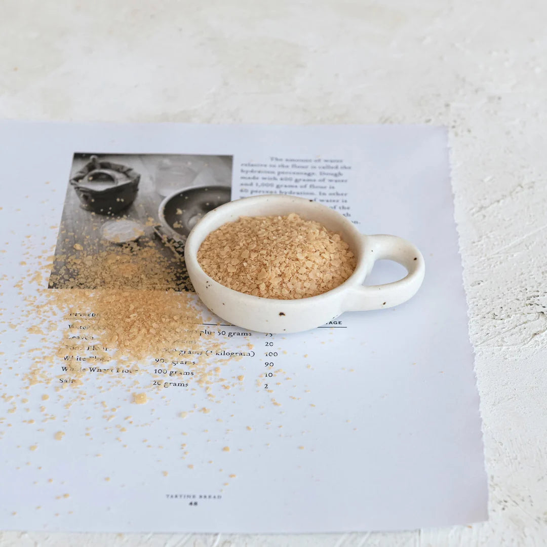 Creative Co-Op Stoneware Dish with Handle holding brown sugar on an open cookbook