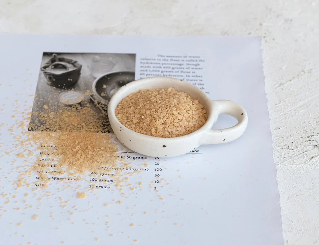 Creative Co-Op Stoneware Dish with Handle holding brown sugar on an open cookbook