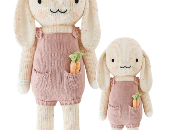 Cuddle + Kind Harper the Bunny, a hand-knit cream bunny doll in pink overalls holding a carrot, shown in two sizes