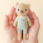 Hands holding the Cuddle + Kind Tiny Charlie the Honey Bear knit doll