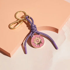 Cai & Jo Bag Charm Keychain, fifth view, daystar bag charm with a purple cord and gold ring