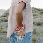 Desert Sol Satin Silk Scrunchie in Apricot Floral on a wrist, with hair clips in the back pocket
