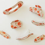 Desert Sol Brushed Sand Floral acrylic hair clip set with an oval lay flat claw clip, classic claw clip, petal claw clip and snap clips with red and coral flowers