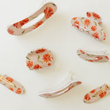 Desert Sol Brushed Sand Floral acrylic hair clip set with an oval lay flat claw clip, classic claw clip, petal claw clip and snap clips with red and coral flowers
