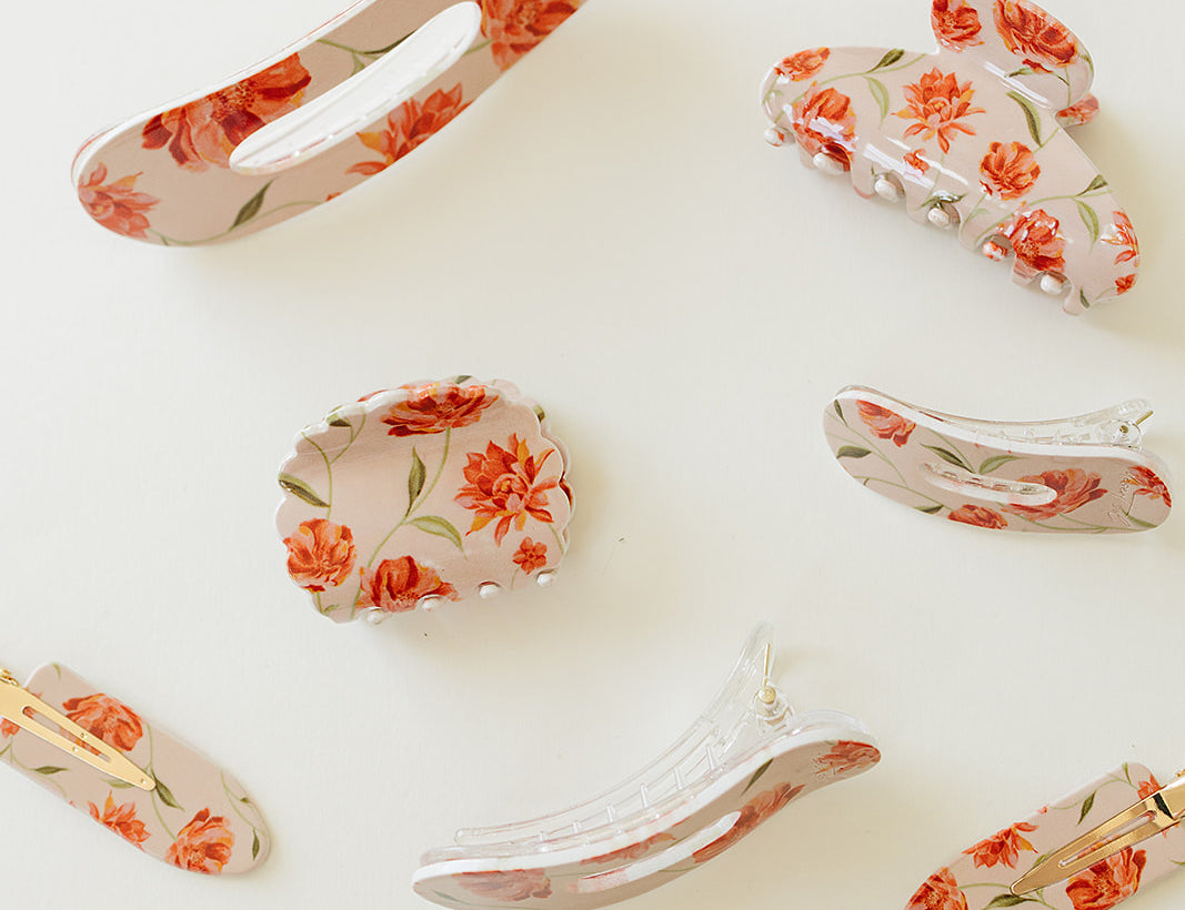 Desert Sol Brushed Sand Floral acrylic hair clip set with an oval lay flat claw clip, classic claw clip, petal claw clip and snap clips with red and coral flowers