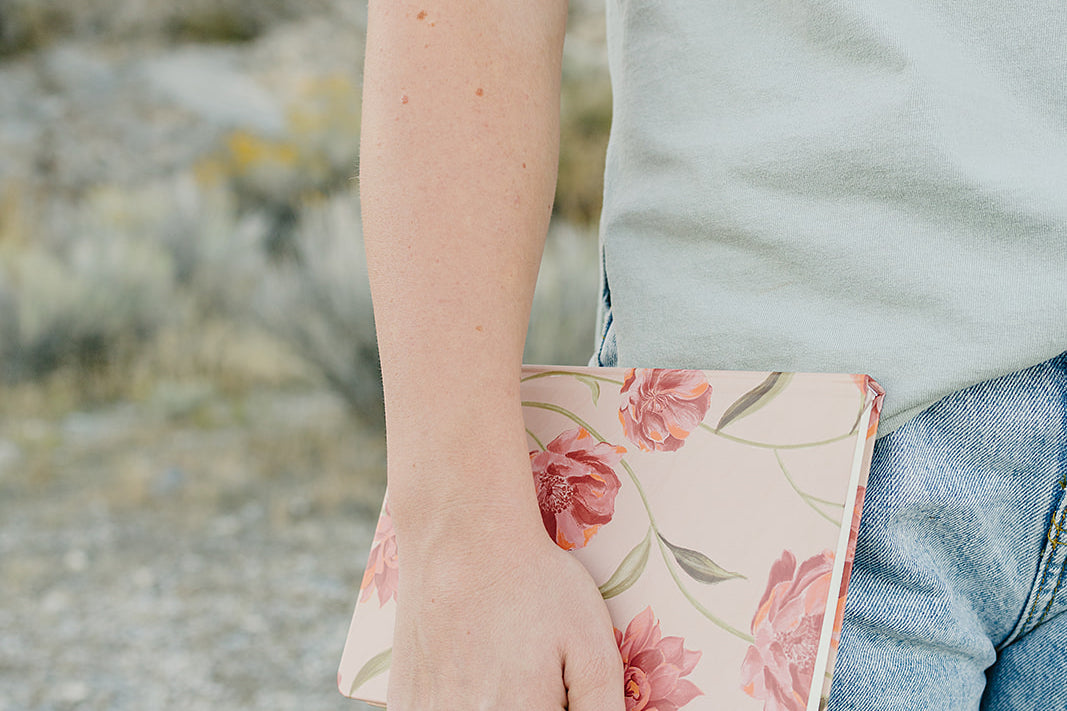 Model holding the Desert Sol Floral Gesture hardcover notebook in Brushed Sand Floral