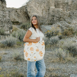 Model carrying the Desert Sol Carryall Tote in Apricot Floral