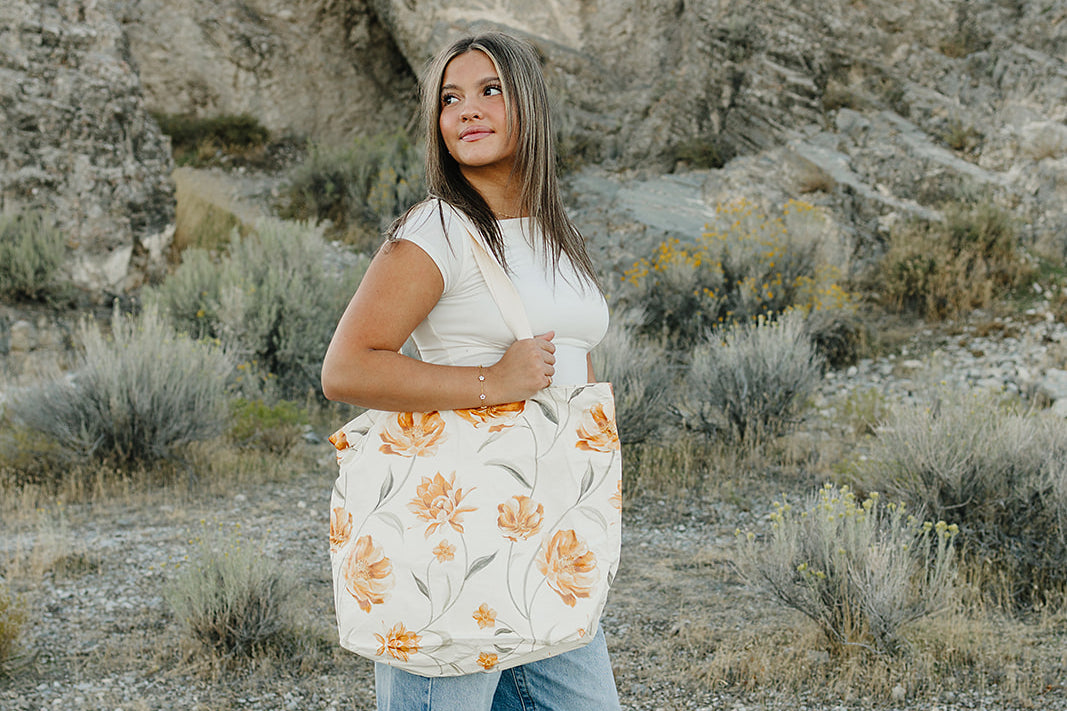 Model carrying the Desert Sol Carryall Tote in Apricot Floral
