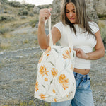 Model opening the Desert Sol Carryall Tote in Apricot Floral