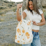 Model opening the Desert Sol Carryall Tote in Apricot Floral