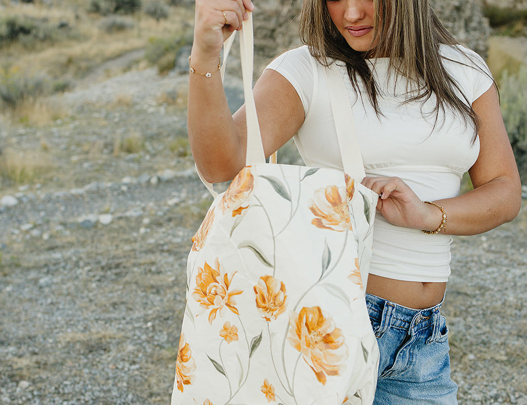 Model opening the Desert Sol Carryall Tote in Apricot Floral