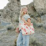 Model smiling with the Desert Sol Carryall Tote in Brushed Sand Floral on her shoulder