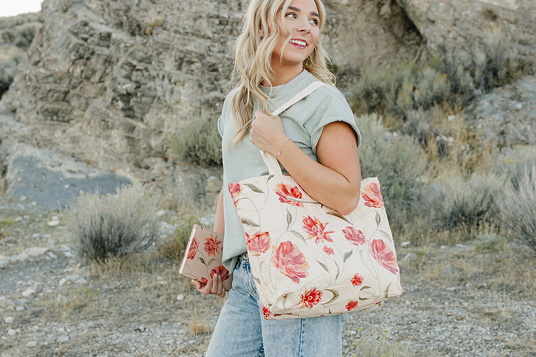 Model smiling with the Desert Sol Carryall Tote in Brushed Sand Floral on her shoulder