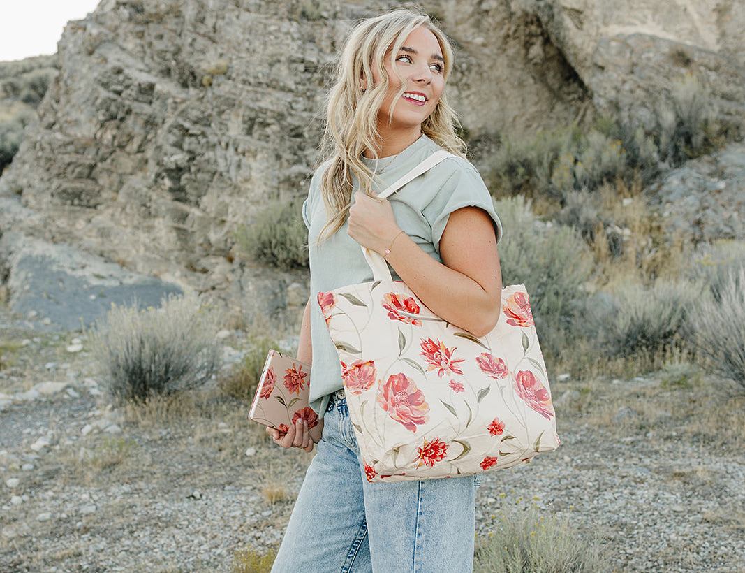 Model smiling with the Desert Sol Carryall Tote in Brushed Sand Floral on her shoulder