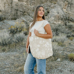 Model carrying the Desert Sol Carryall Tote in Canyon Rose in the desert