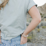 Desert Sol Mulberry Silk Scrunchie in Champagne worn on the wrist with a sage tee