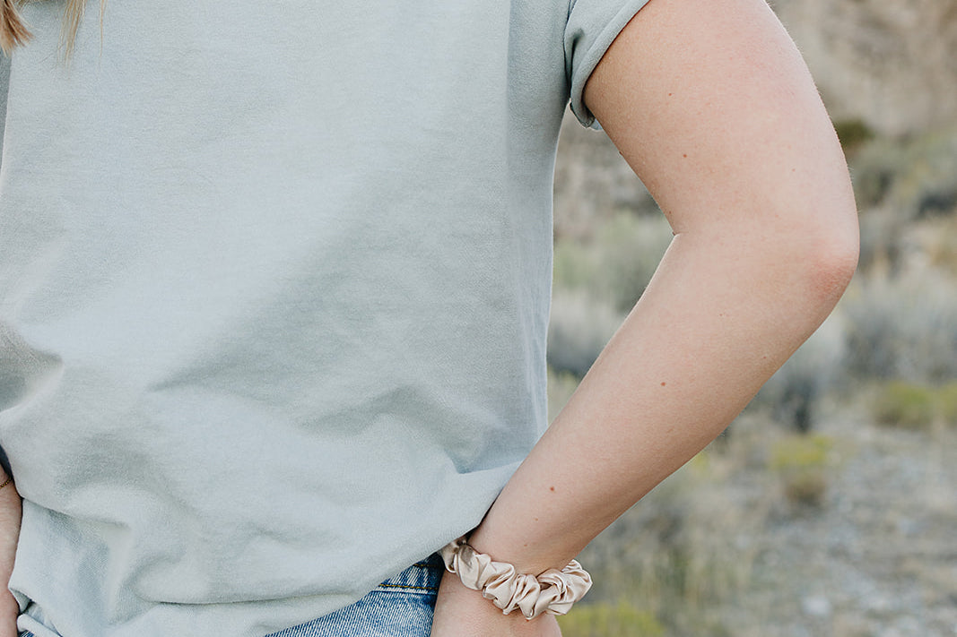 Desert Sol Mulberry Silk Scrunchie in Champagne worn on the wrist with a sage tee