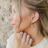 Model in profile wearing the Desert Sol Dainty Hoop Earrings in gold against desert rock