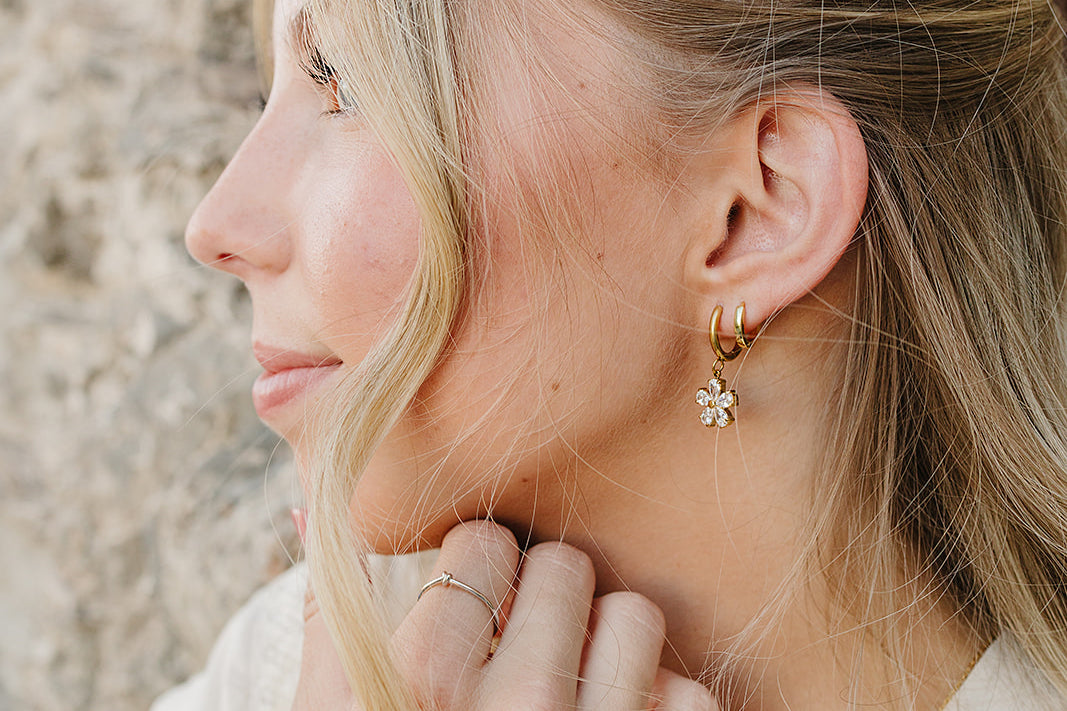 Model in profile wearing the Desert Sol Dainty Hoop Earrings in gold against desert rock