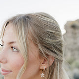 Close up of the Desert Sol Dainty Hoop Earrings in gold on a model with long blonde waves
