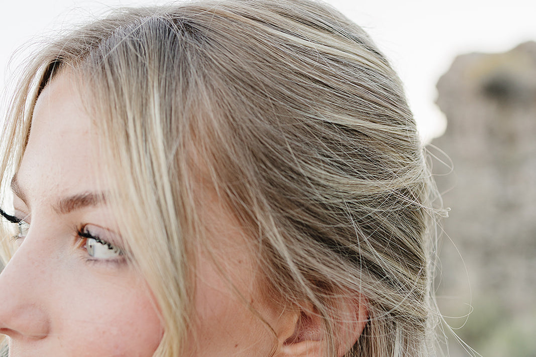 Close up of the Desert Sol Dainty Hoop Earrings in gold on a model with long blonde waves
