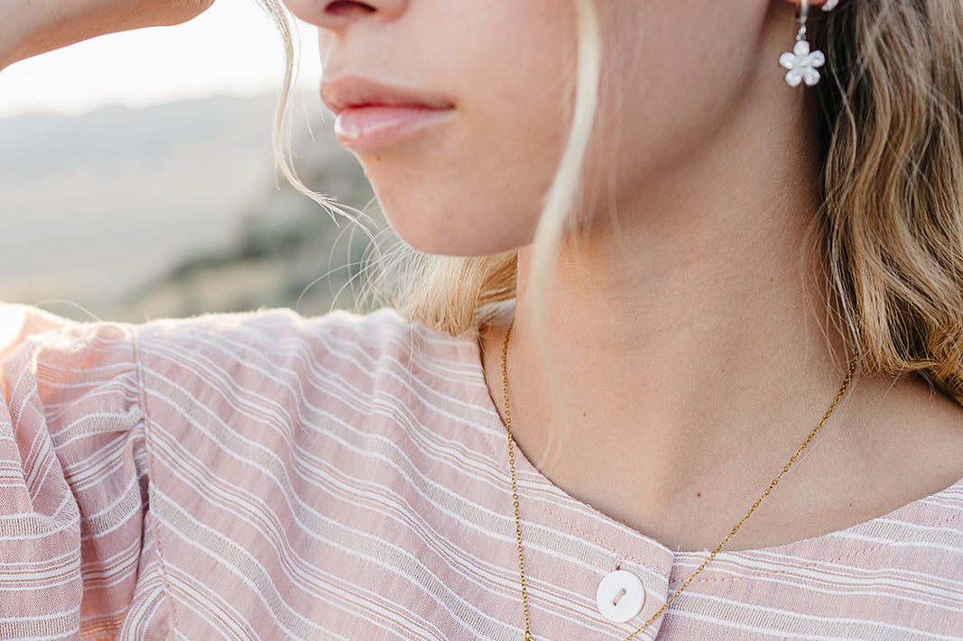 Model wearing the Desert Sol Dainty Hoop Earrings in silver with a crystal flower drop