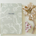 Desert Sol Desert Intentions To Do notebook with a champagne silk scrunchie and Mulberry Floral claw clip