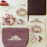 Desert Sol Desert Mesa corduroy pouch and Desert Plum journal laid flat with Mulberry Floral and silk scrunchies, claw clips and gold jewelry