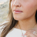 Close up of the Desert Sol Ember Butterfly Necklace in Blush Pink on a delicate gold chain