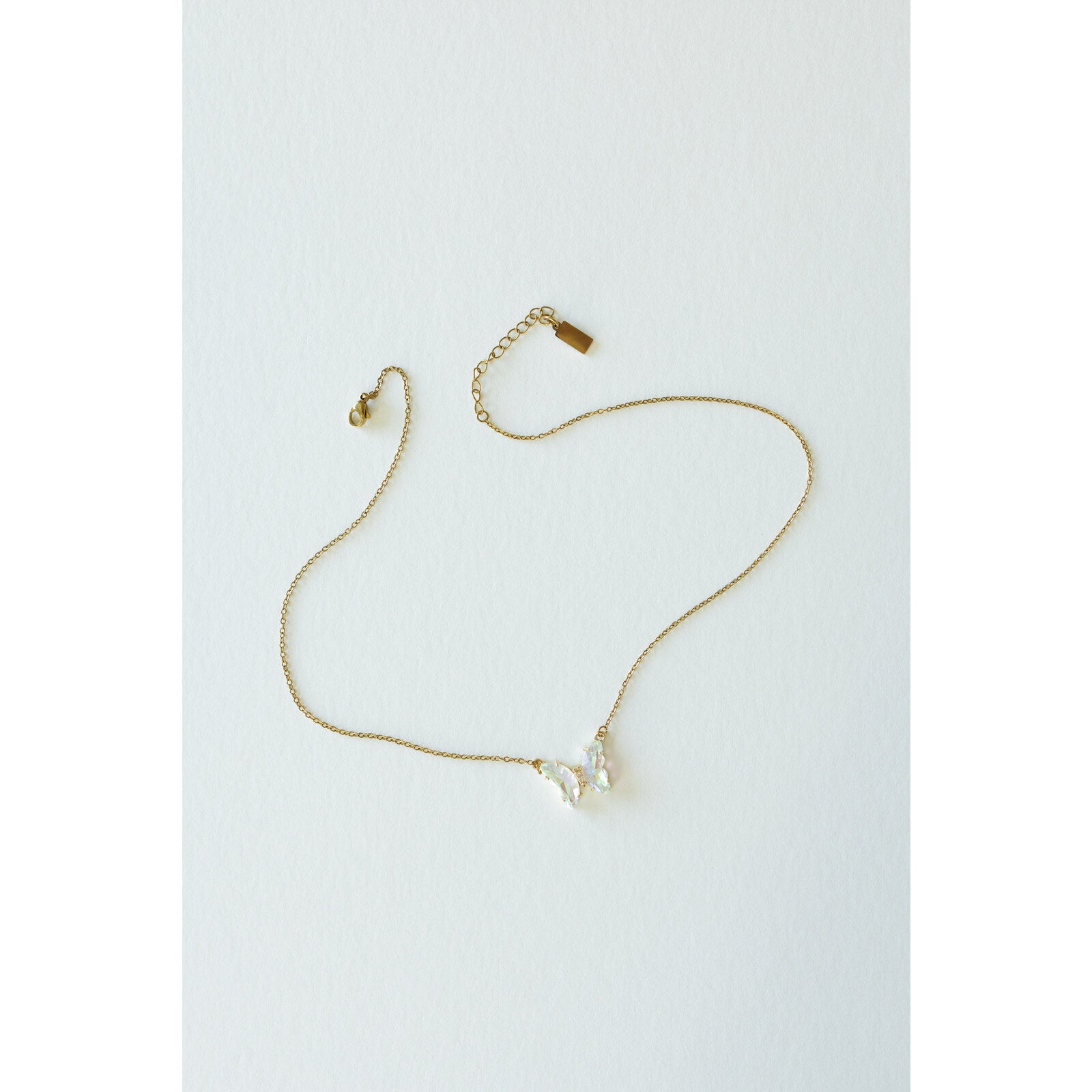Desert Sol Ember Butterfly Necklace in opal white, a faceted crystal butterfly pendant on a warm gold chain, on a white background