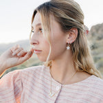 Model wearing the Desert Sol Ember Butterfly Necklace in Opal White with Dainty Hoop Earrings in silver and a Sundust Pave Huggie