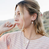Model wearing the Desert Sol Ember Butterfly Necklace in Opal White with Dainty Hoop Earrings in silver and a Sundust Pave Huggie