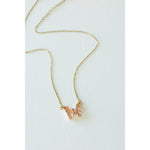 Desert Sol Ember Butterfly Necklace in peach, a faceted crystal butterfly pendant on a warm gold chain, on a white background