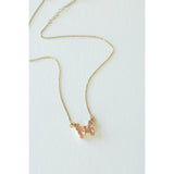 Desert Sol Ember Butterfly Necklace in peach, a faceted crystal butterfly pendant on a warm gold chain, on a white background