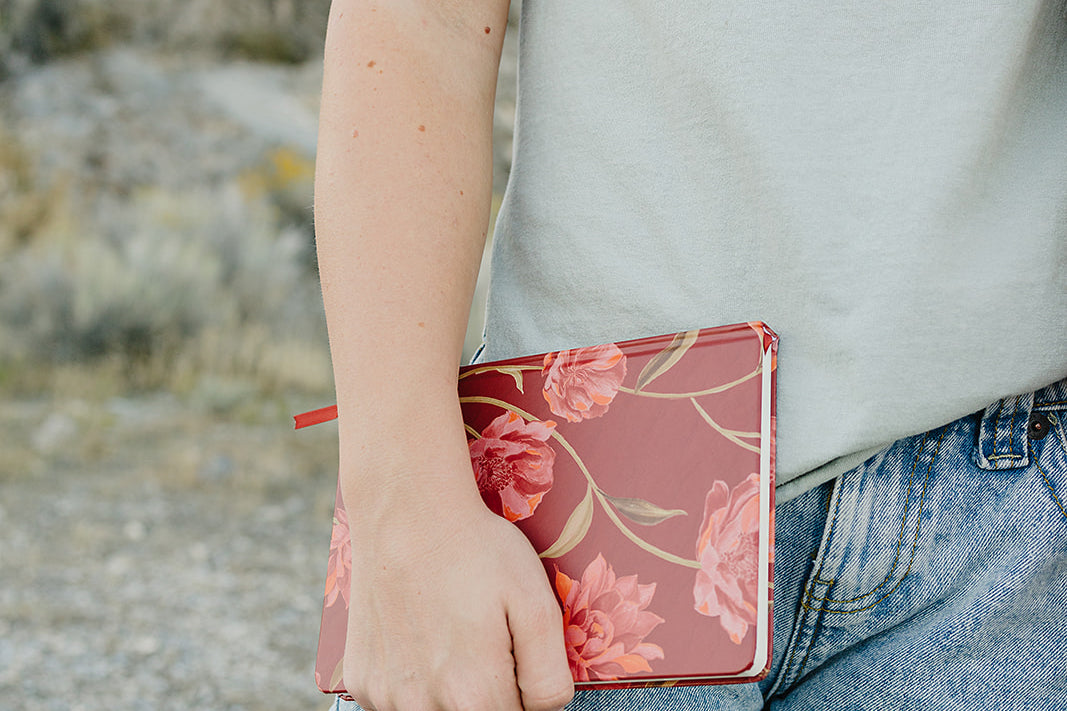 Model holding the Desert Sol Floral Gesture hardcover notebook in Ember Floral