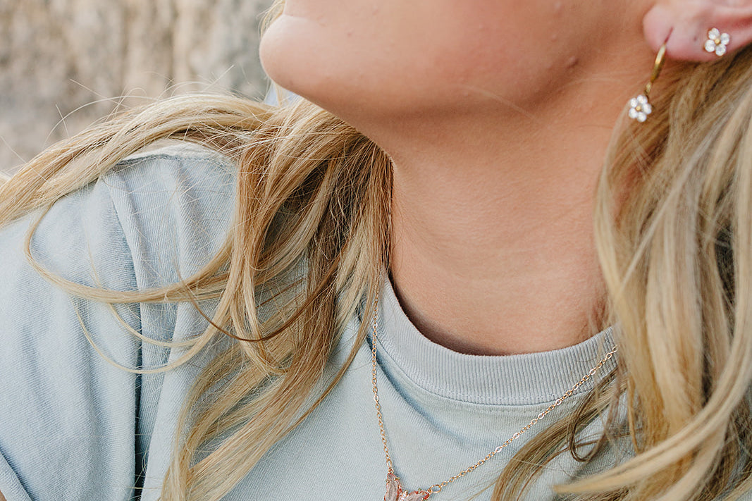 Smiling model wearing the Desert Sol Everflight Butterfly Necklace in Petal Pink with a sage tee