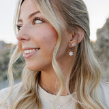 Model smiling in the Desert Sol Fleur Hoop Earrings in silver and a delicate silver necklace