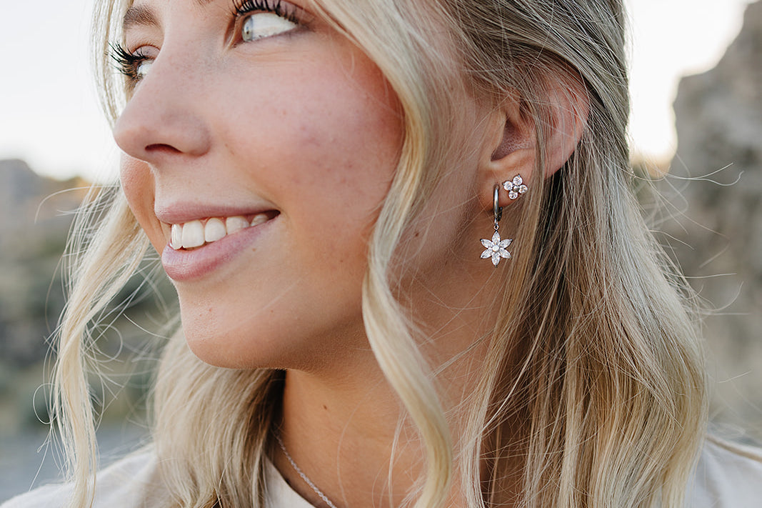 Model smiling in the Desert Sol Fleur Hoop Earrings in silver and a delicate silver necklace
